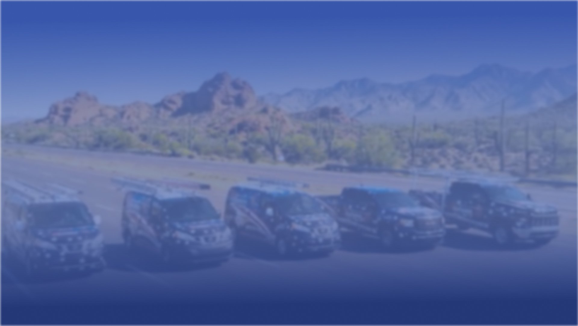 Row of Autumn Air service vans parked in the desert with a mountain backdrop.