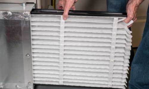 Senior caucasian man changing a folded air filter in the HVAC furnace system in basement of home