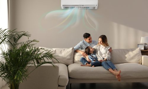 Happy family resting under air conditioner on beige wall at home